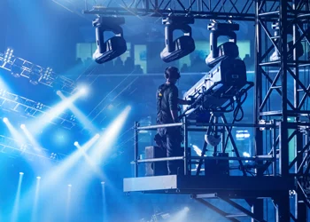 Technicians installing stage lighting fixtures on overhead truss system