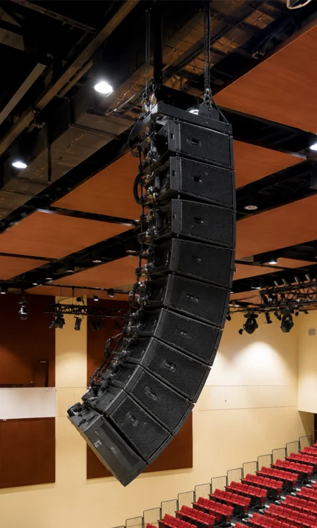 Auditorium Line Array Speaker Installation Suspended line array speaker system installed below warm acoustic ceiling panels in a modern auditorium.