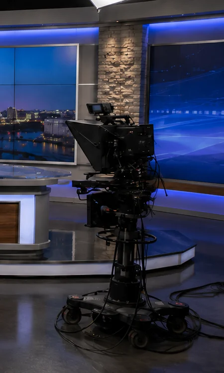 Regional TV News Studio Empty regional TV news studio with anchor desk, broadcast cameras, teleprompters, and studio lighting